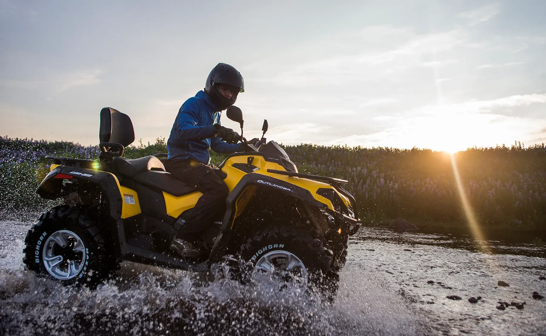 ATV splashing through water at sunset