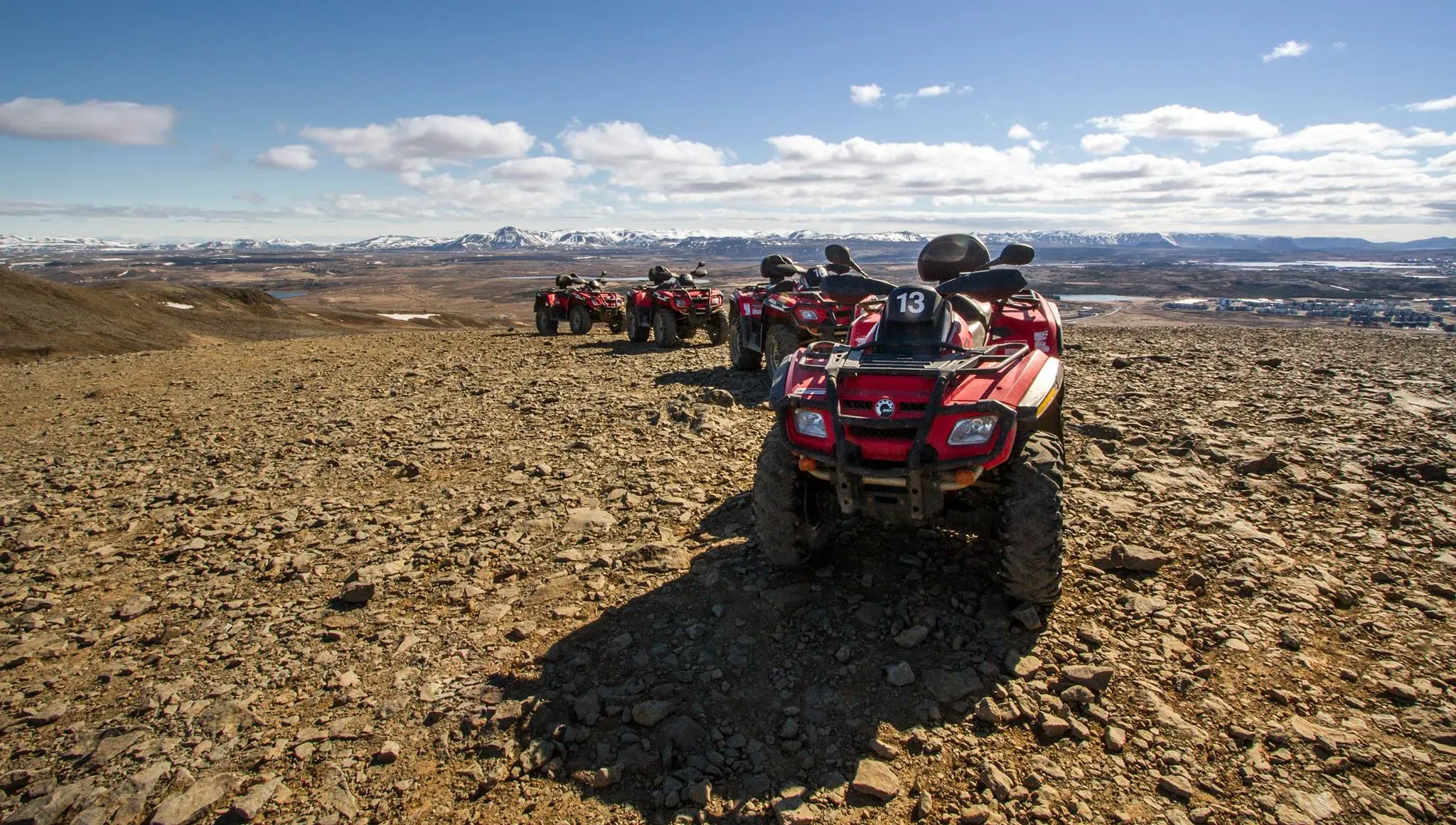 Line of red ATVs parked on a rocky summit