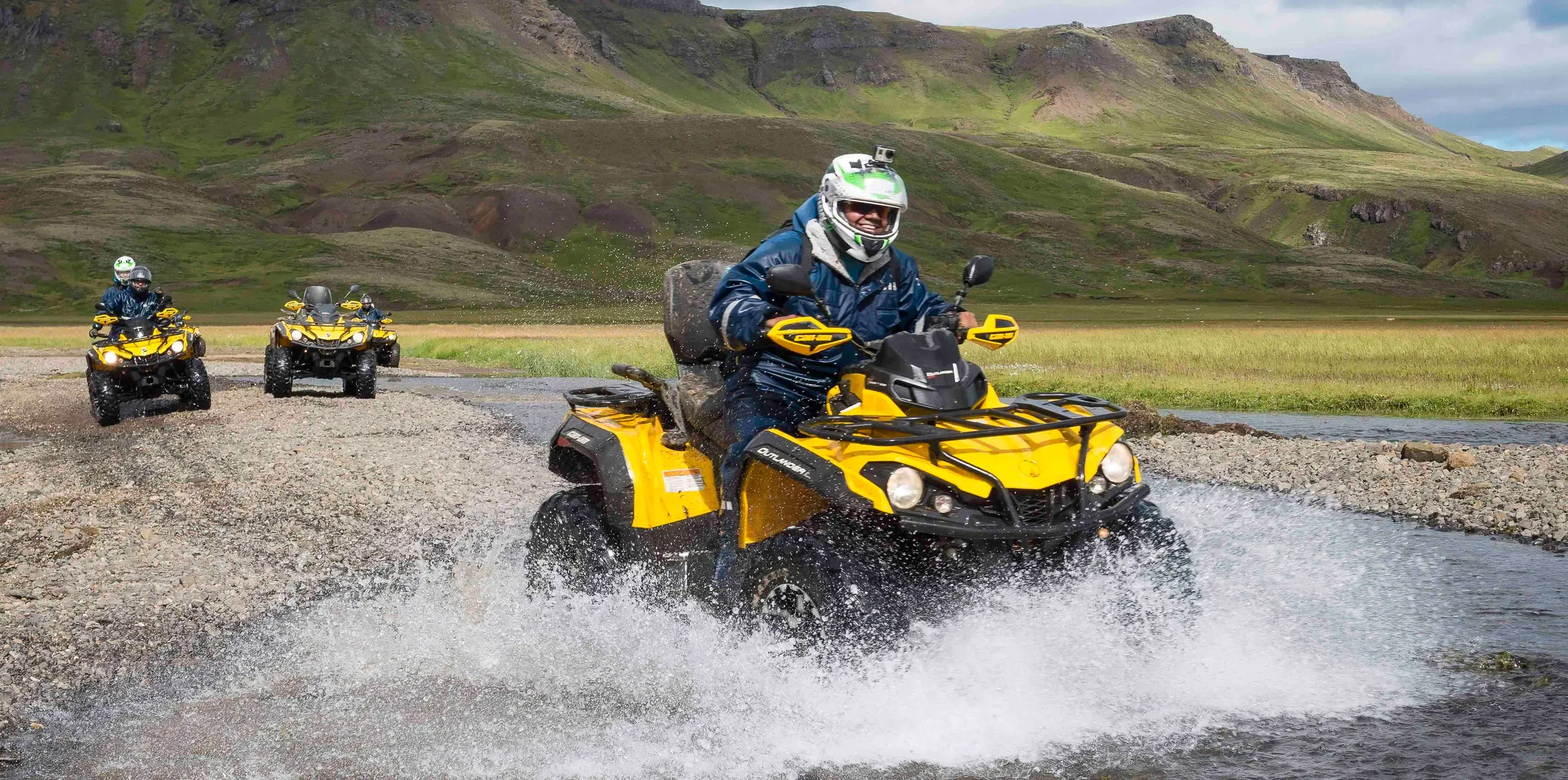 Rider on a yellow ATV crossing a river