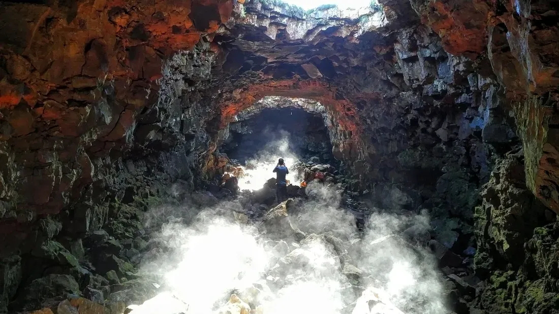 Steam rising in a lava tunnel lit from above