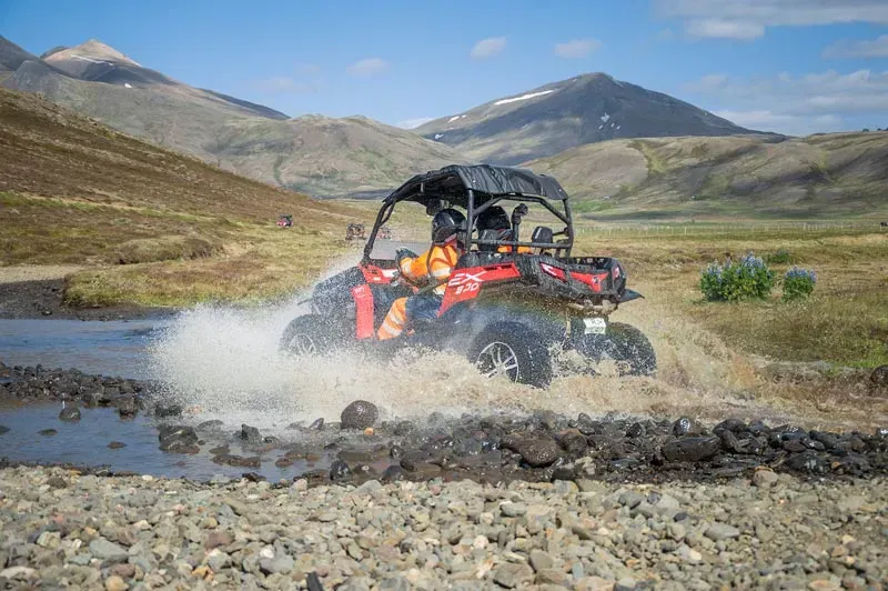 Buggy splashing through a river in a green mountain valley