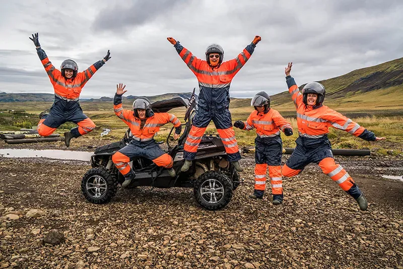 Group in orange overalls jumping for joy beside a buggy