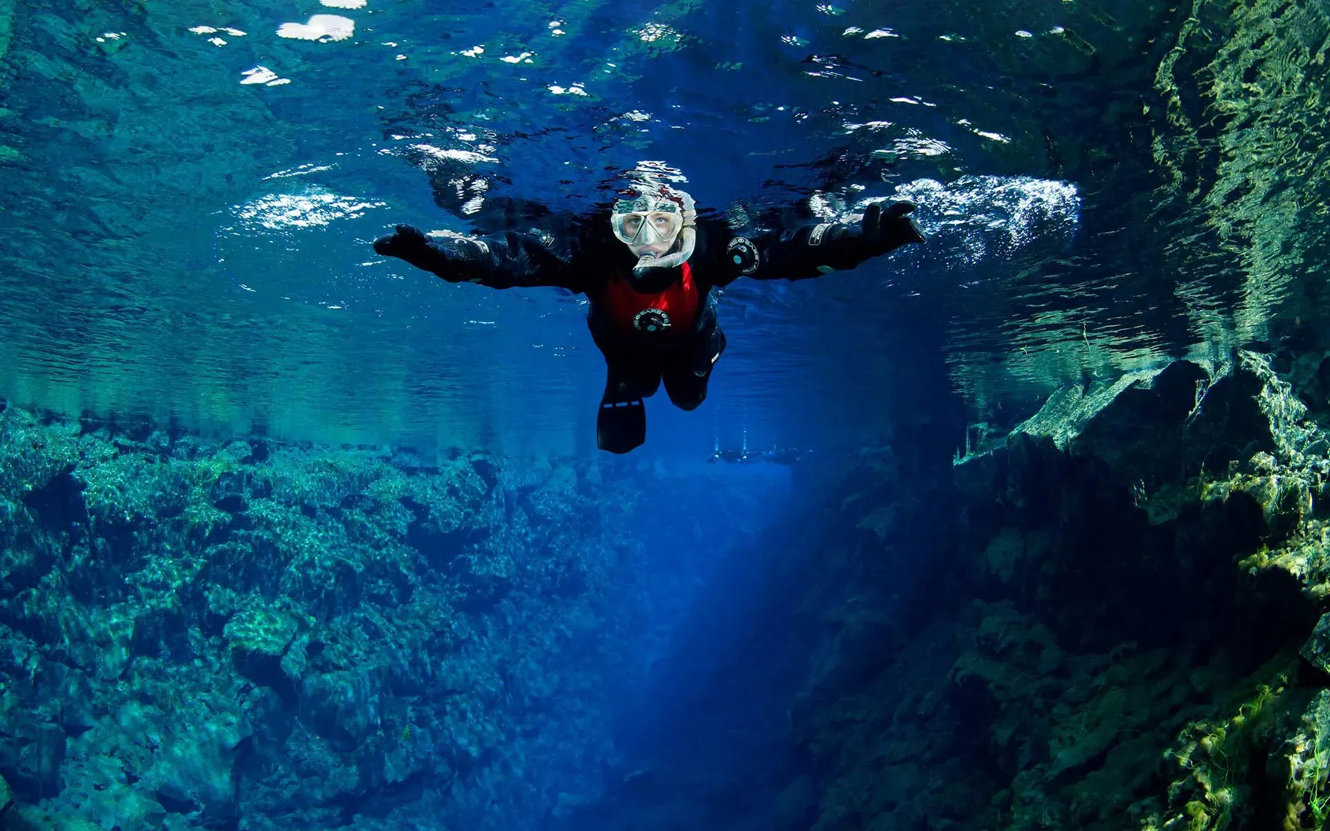 Snorkeller floating in the clear water of Silfra