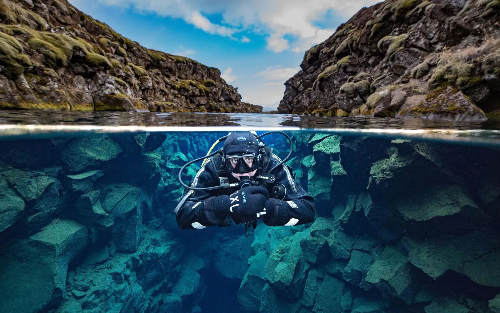 Diver in the Silfra fissure, half above and half below the water line