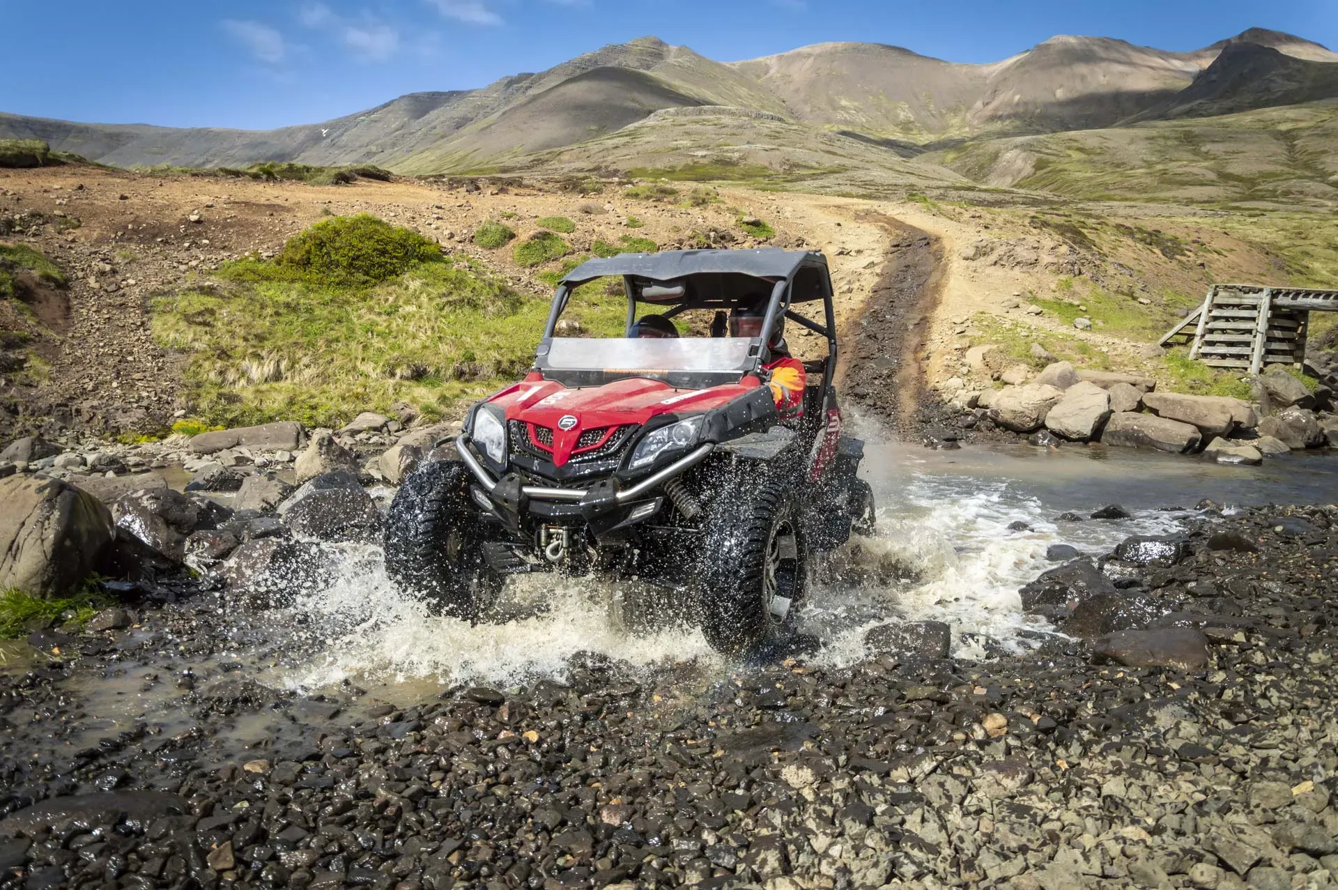 Red buggy splashing through a stream on a mountain track