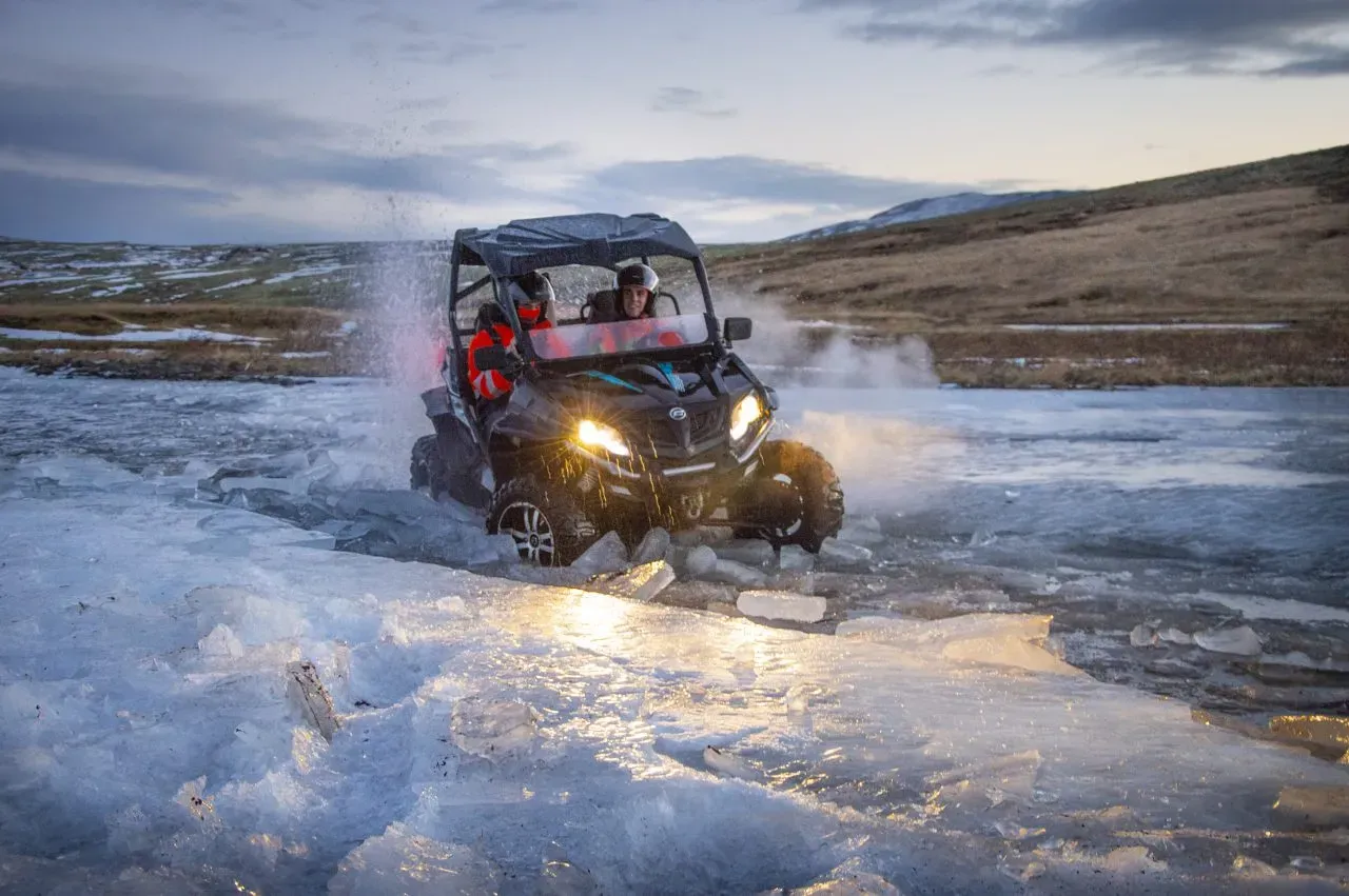 Buggy with its headlights on driving through icy water