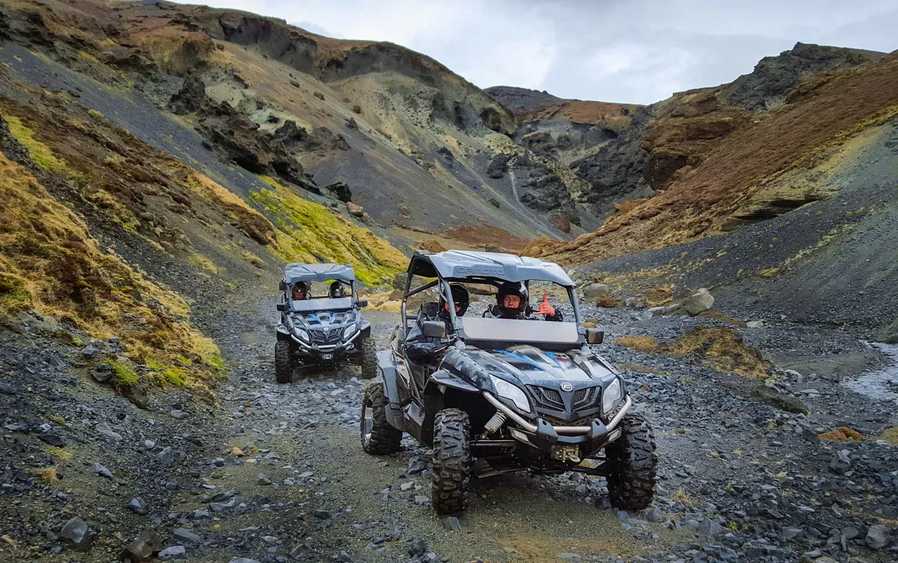Two buggies on a gravel track in a colourful mountain valley