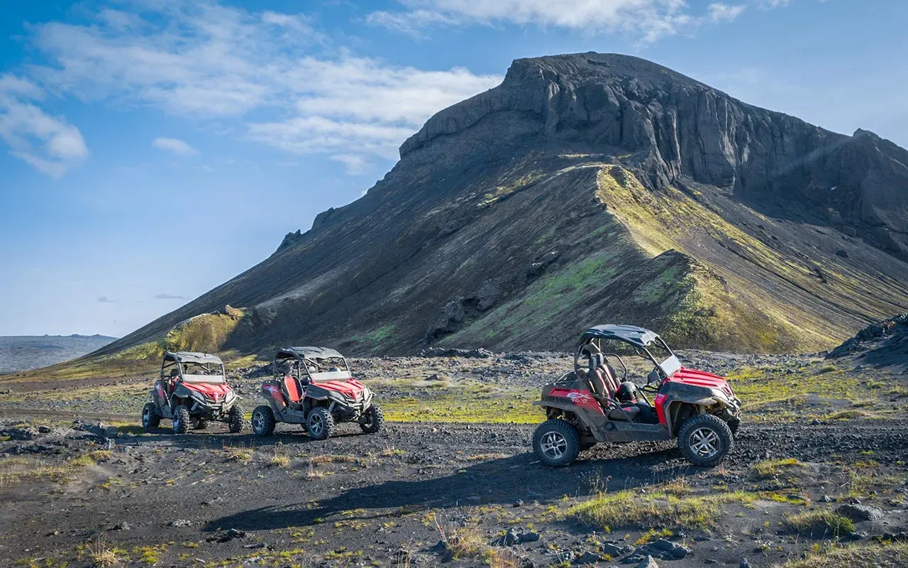 Three buggies below a steep flat-topped mountain