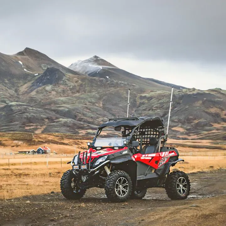 Red buggy parked on a gravel plain below the mountains