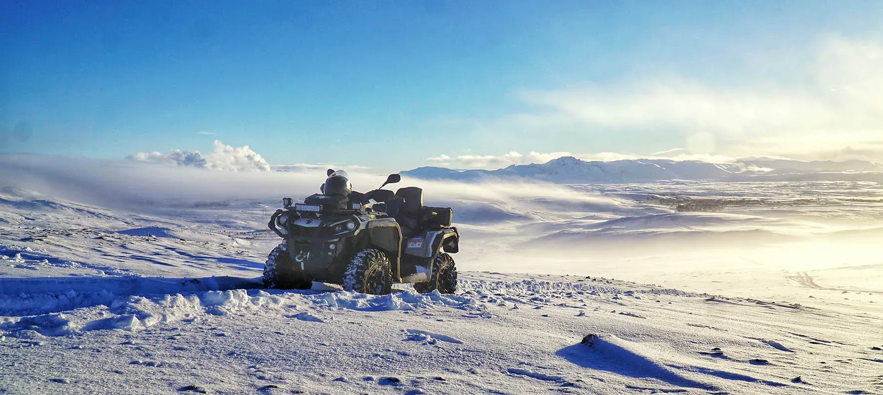 ATV on a snowy mountain top with a view across the lowlands